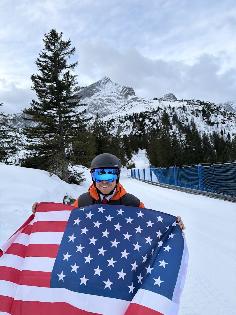 Ahmed in winter gear holding an American flag in the snow