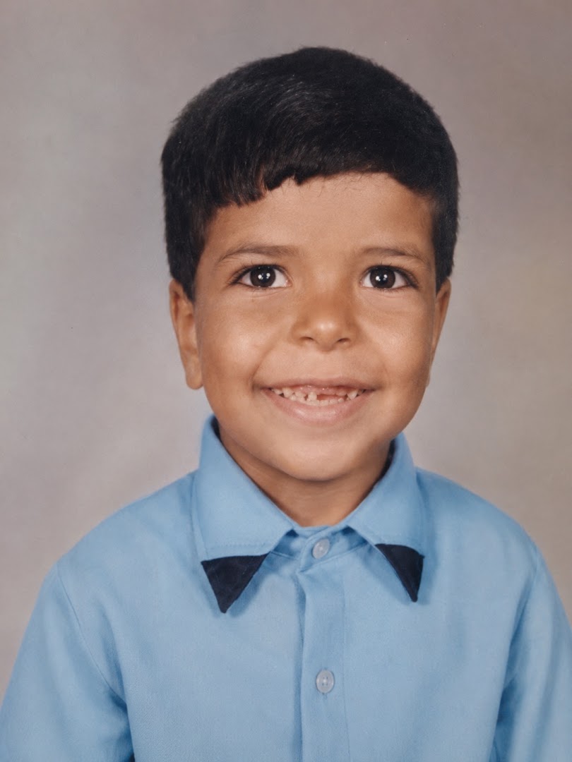 Ahmed as a young child, smiling in a blue shirt